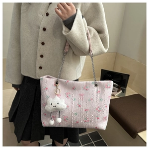 Detail of pink floral tote bag with wrinkled texture, silver chain, and cloud charm