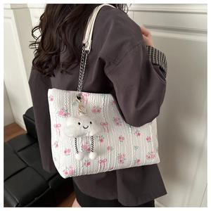 Detail of floral quilted shoulder bag with plush cloud charm and metal chain strap