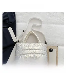 Detail showing shiny silver quilted tote bag with adjustable strap on white fabric
