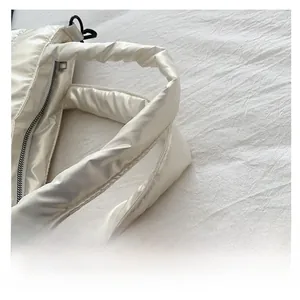 Close-up of comfortable padded handles on a white quilted nylon shoulder bag for women