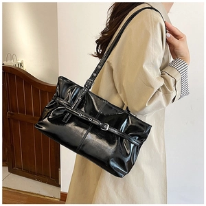 Detail of glossy black patent leather tote with silver buckle and belt accents