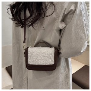 Detail showing the brown leather and white faux shearling crossbody bag on a trench coat