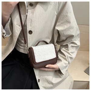 Detail of vintage shearling and leather saddle bag worn as a crossbody with metal clasp