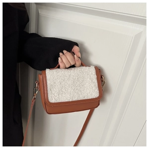 Close-up of brown faux leather handbag with white faux fur trim and gold hardware
