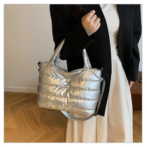 Silver quilted down-style crossbody bag with metallic finish and woven shoulder strap