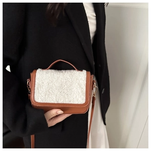 Detail of caramel leather saddle bag with white shearling flap and gold hardware
