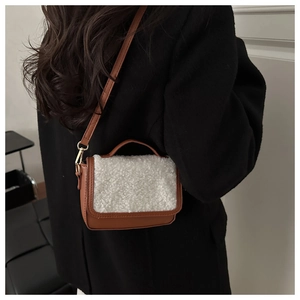Brown leather saddle bag with white fleece detail worn over a black wool coat