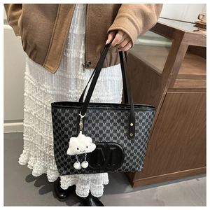 Close-up of monogram pattern and plush cloud charm on a stylish large capacity tote bag
