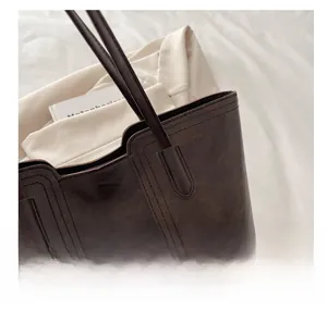 Close-up of retro brown tote bag showing durable double-stitched leather texture