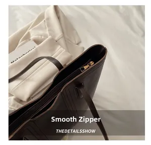 Detail view of smooth golden zipper and premium dark brown leather on large tote bag