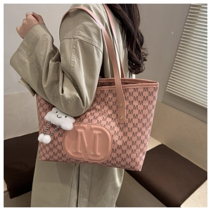 Pink tote bag with repetitive M pattern and plush cloud charm shown on model's shoulder