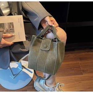 Close-up of olive green bucket bag with white contrast stitching and round buckle detail