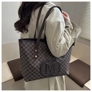 Detail of vintage tote bag with M-pattern print and embossed leather logo patch