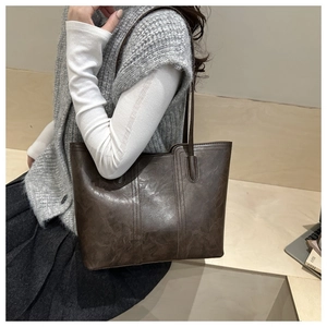 Detail of dark brown oil wax leather tote bag worn on shoulder for commute aesthetic
