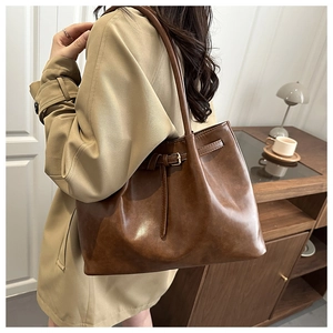 Close-up of retro brown leather tote bag on shoulder with fine strap and buckle details