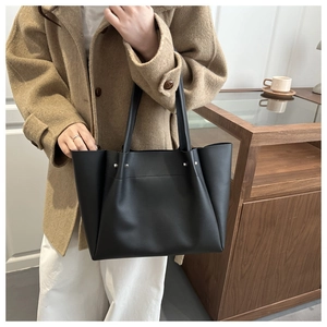 Side detail of large black tote bag with silver hardware on a wool coat outfit
