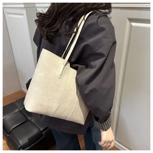 Detail of off-white suede tote bag with contrast stitching on a model's shoulder