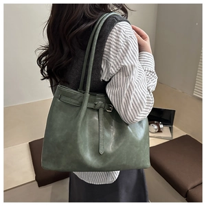 Detail of dark green tote bag with matte leather texture and decorative belt buckle strap
