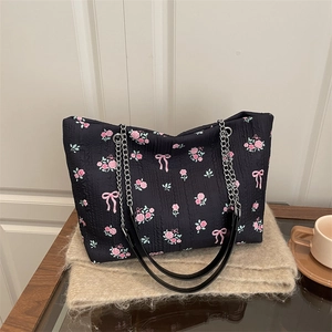 Floral print black tote bag with pink roses, ribbon bows, and a silver chain strap