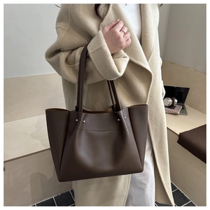 Detail of dark brown leather tote bag with silver rivets and large capacity shoulder strap