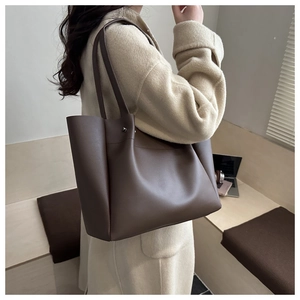 Deep brown large tote bag styled in a modern minimalist office setting with a laptop