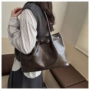 Detail of dark brown leather tote bag with metallic buckle strap decoration