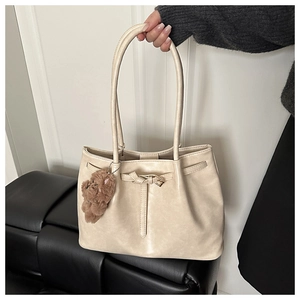 Detailed close-up of beige PU leather tote bag with gold buckle and teddy bear charm