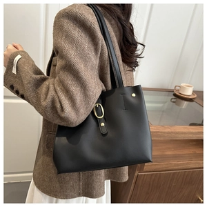 Détail d'un sac cabas en cuir noir mat avec boucle dorée élégante porté par un mannequin
