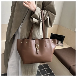 Dettaglio della borsa tote in pelle marrone con fibbia dorata vintage e rivetti