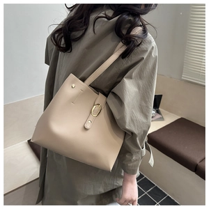 Detail view of beige tote bag with golden buckle and sleek synthetic leather texture