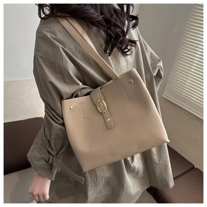Dettaglio borsa tote beige caffè con fibbia dorata e tracolla indossata da una modella