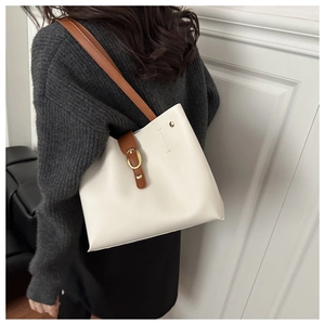 Dettaglio borsa tote minimalista con fibbia in pelle marrone e finitura crema su modella