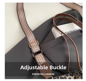 Detail of adjustable metal buckle and pink-grey woven strap on leopard print bag