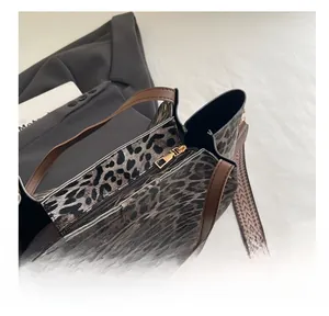 Detail view of leopard print tote featuring metal zipper and ethnic woven shoulder strap