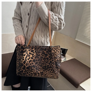 Detail of a leopard print tote bag with brown straps and metal side hooks in a daily scene