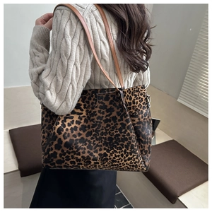 Detail of leopard print tote bag with brown leather straps and metal hardware accents