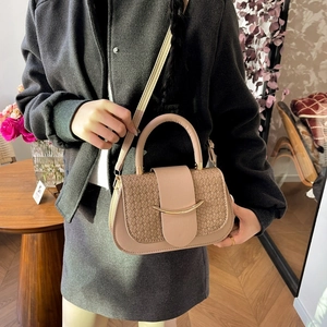 Détail de la texture tissée beige et du fermoir en métal doré sur un sac à main structuré