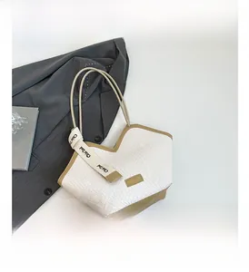 Dettaglio della borsa tote intrecciata bianca con manici kaki e nastro decorativo