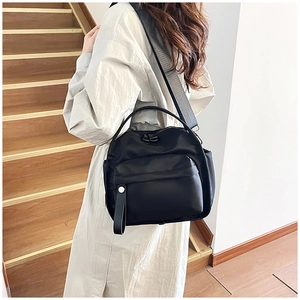 Detail of black nylon shoulder bag with adjustable grey strap and silver zipper