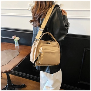 Detail of beige nylon crossbody bag featuring wide shoulder straps and large front pocket