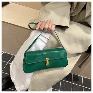 Detail of emerald green patent leather handbag with golden horseshoe lock closure