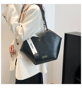 Dettaglio borsa vintage nera con apertura a V e trama intrecciata su un blazer elegante
