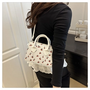 Détail du mini sac blanc à imprimé cerise avec bandoulière assortie et poignée