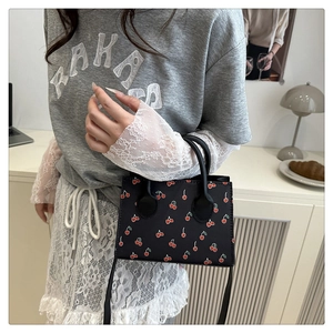 Detail of cute cherry print small crossbody bag in black PU leather with top handle