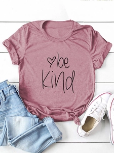 Close-up of be kind graphic print on rose pink t-shirt with denim and white sneakers