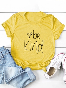 Detail view of yellow t-shirt with be kind text, knot hem and casual accessories