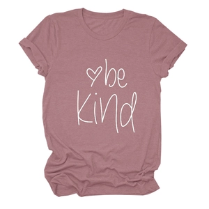 Detailed close-up of 'be Kind' white script print on dusty rose cotton t-shirt fabric