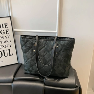 Minimalist black quilted tote bag with camo pattern and golden rivet leather straps