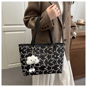 Detail of black star-stitched tote bag with white cloud charm on model arm