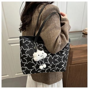 Detail of black star quilted tote bag featuring a plush cloud charm on a shoulder strap
